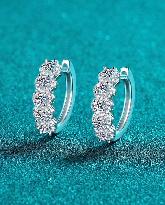 Pair of silver hoop earrings, each set with a row of five round clear stones.